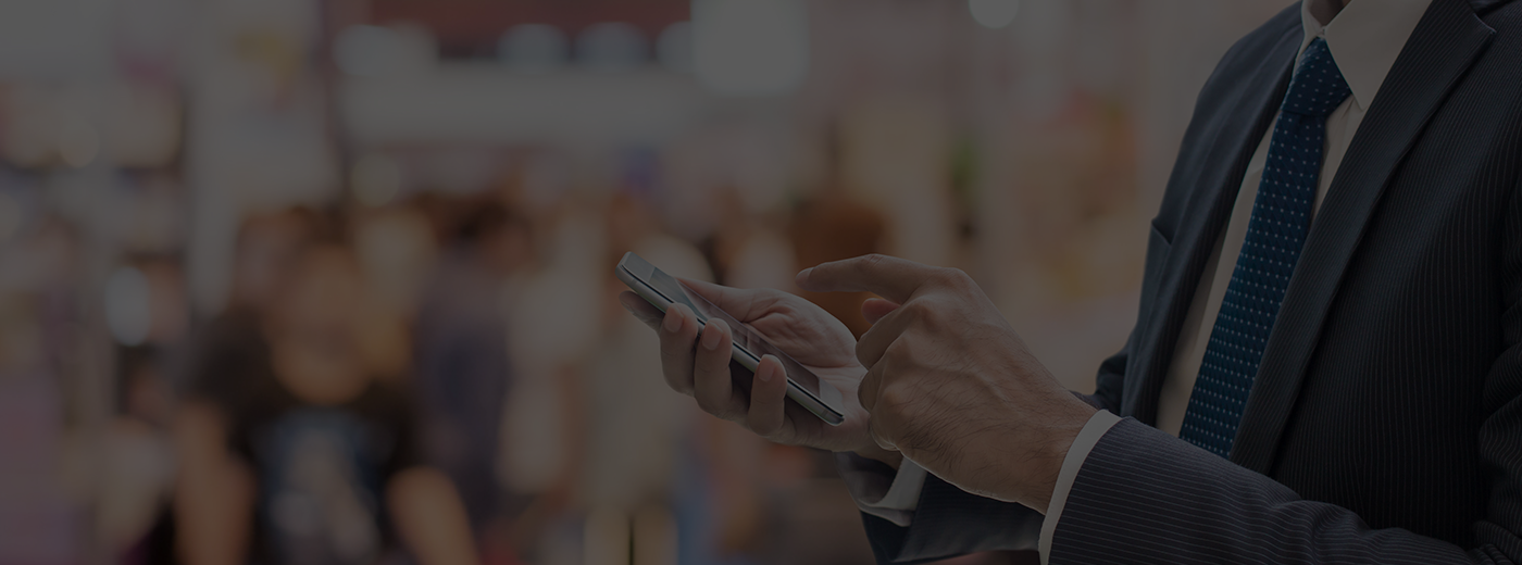 Businessman using smartphone Communicate at trade shows exhibition hall with full of people walking blurred background
