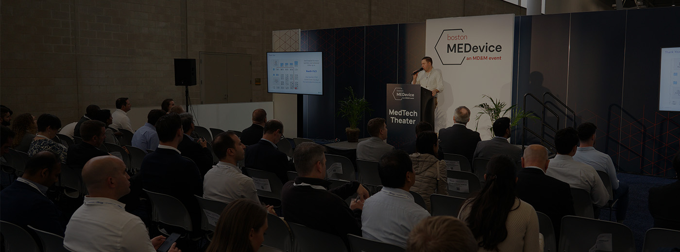 A man stands at a podium, delivering a presentation to audience at MEDevice Boston conference