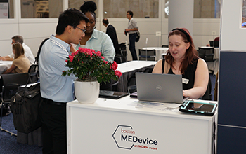 A man and woman collaborate at a desk, engaged with a laptop