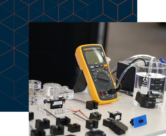  A table displaying various electronic devices alongside a multimeter for measuring electrical properties